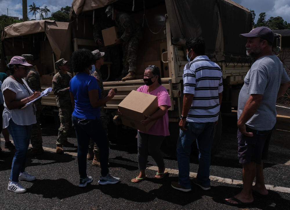 People in Orocovis line up to get food and other supplies being handed out by member of the National Guard and the Department of Family of Puerto Rico.