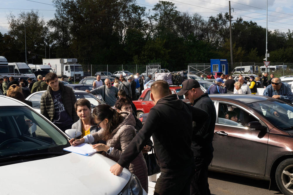 People from Russian-occupied places like Melitopol and Kherson arrive in a convoy of cars to the parking lot of a home goods store set up as a makeshift welcome center in Zaporizhzhia, Ukraine.
