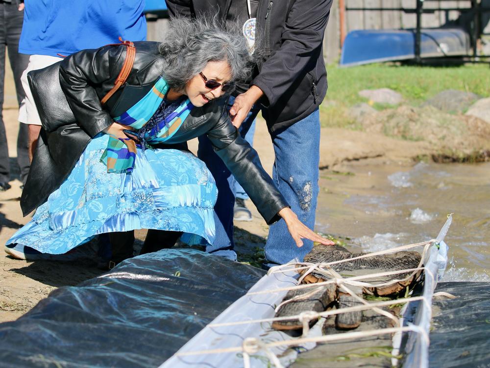 A woman from the Ho-Chunk Nation smiles as she touches the canoe. Wisconsin Historical Society maritime archaeologists recovered a 3,000-year-old dugout canoe from Lake Mendota in Madison, Wis., on Thursday.