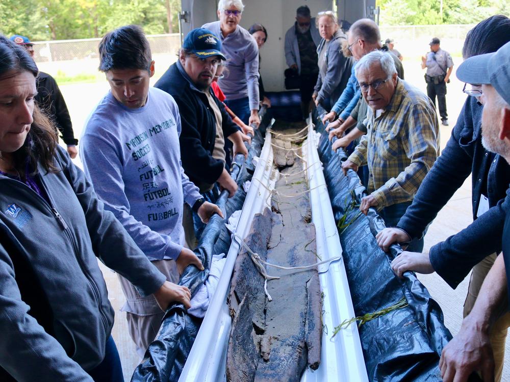 Wisconsin Historical Society staff and volunteers remove the canoe from its transport trailer and carry it into the State Archive Preservation Facility in Madison.