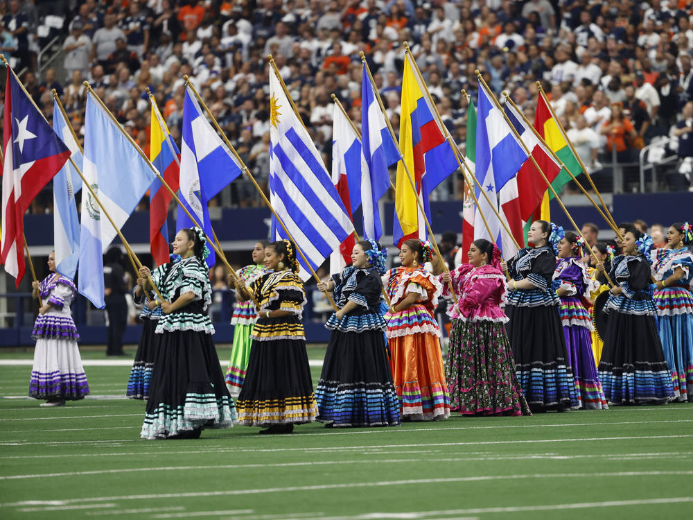 Women hold flags during the national anthem in honor of Hispanic Heritage Month before an NFL game on Sept. 18. The NFL has launched its Por La Cultura campaign.