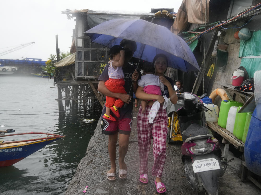 Residents of the Tondo district in Manila carry their children as they evacuate to safer grounds on Sunday before Typhoon Noru arrives in the Philippines.