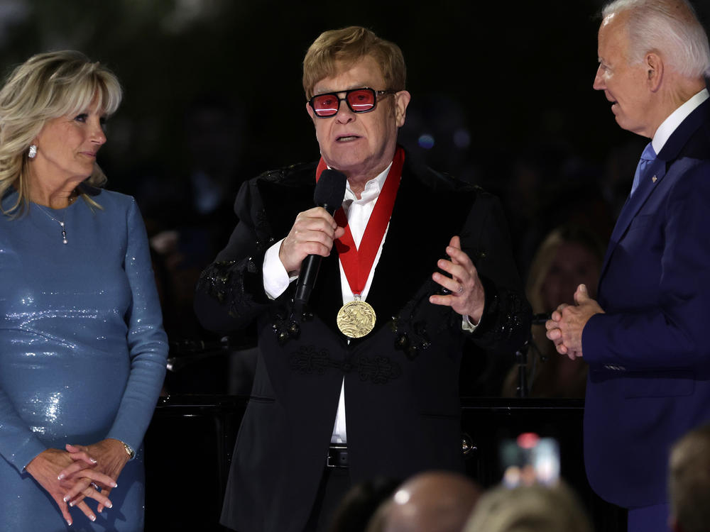 Sir Elton John speaks after being presented with the National Humanities Medal by President Biden as first lady Jill Biden looks on during an event at the South Lawn of the White House on Friday.