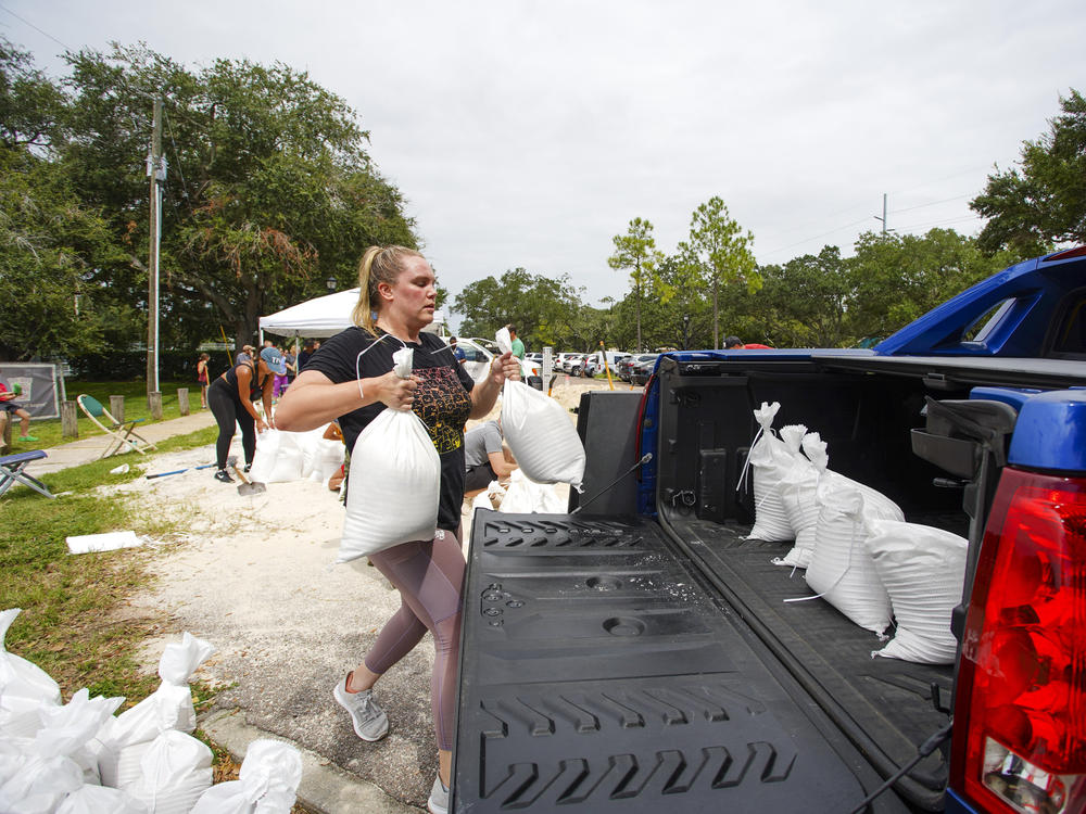 Victoria Colson, 31, of Tampa, Fla., loads sandbags into her truck along with other residents who waited for over 2 hours at Himes Avenue Complex to fill their 10 free sandbags on Sunday.