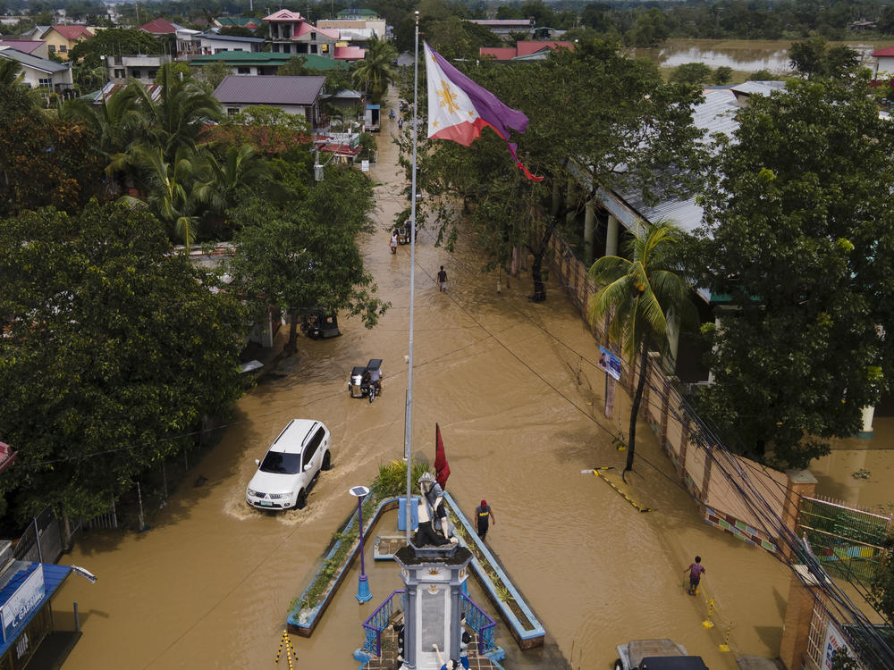 Residents pass by a flooded road from Typhoon Noru in San Miguel town, Bulacan province, Philippines. Typhoon Noru blew out of the northern Philippines on Monday, leaving some people dead, causing floods and power outages and forcing officials to suspend classes and government work in the capital and outlying provinces.