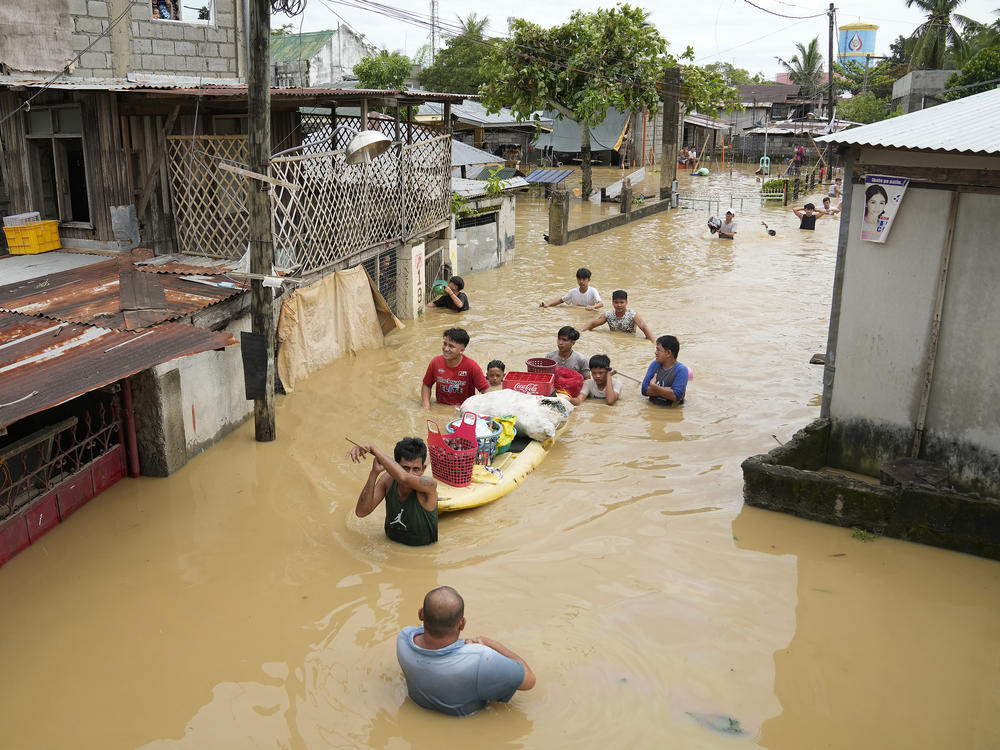 Residents give out free food as they wade through a flooded street in their village from Typhoon Noru in San Miguel town, Bulacan province, Philippines on Monday.