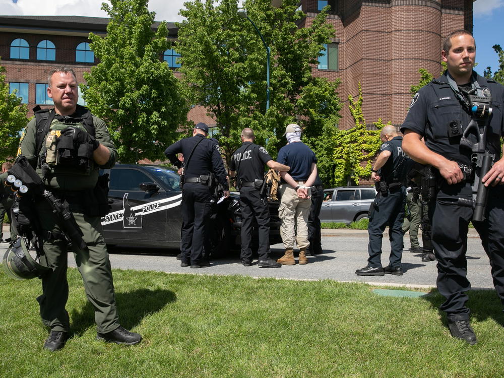 A police officer holds one of a group of men, among 31 arrested for conspiracy to riot and affiliated with the white nationalist group Patriot Front, after they were found in the rear of a U-Haul van in the vicinity of a North Idaho Pride Alliance LGBTQ+ event in Coeur d'Alene, Idaho, on June 11, 2022.
