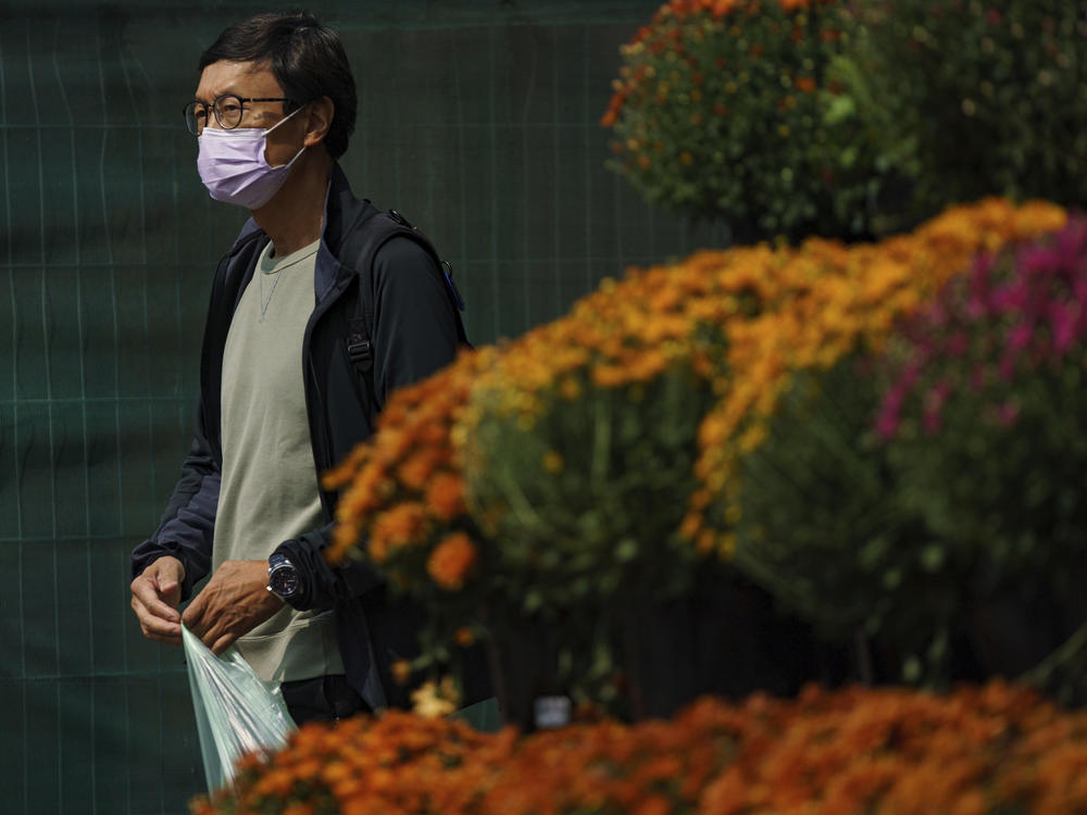 A person wearing a mask walks past a flower display in front of a supermarket on Front Street East in Toronto on Sept. 16.