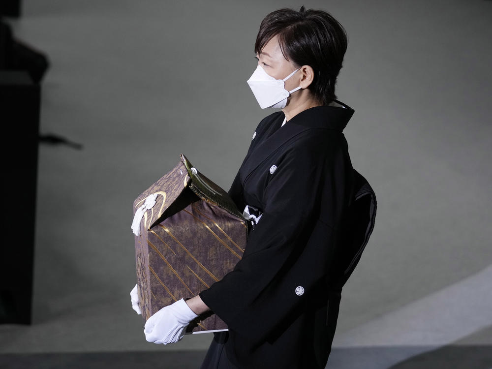 Akie Abe, wife of former Prime Minister Shinzo Abe, carries a cinerary urn containing his ashes at his state funeral, Tuesday, Sept. 27, 2022, in Tokyo.