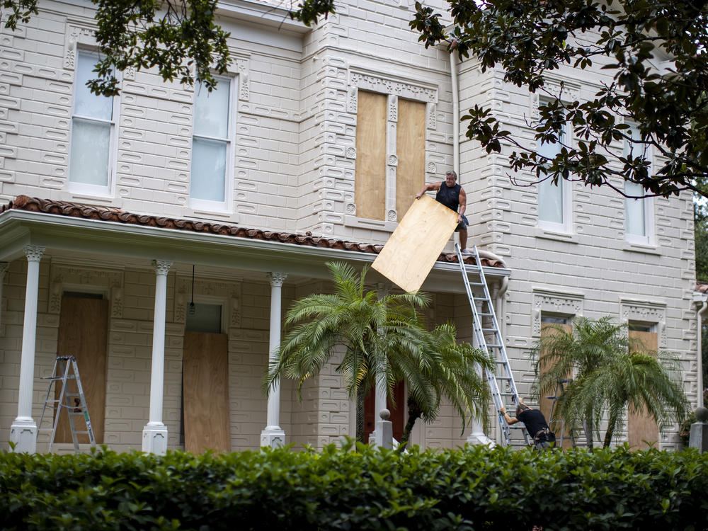 Two people work on boarding up a house in South Tampa Bay, Florida, on Tuesday, before Hurricane Ian hits the area.