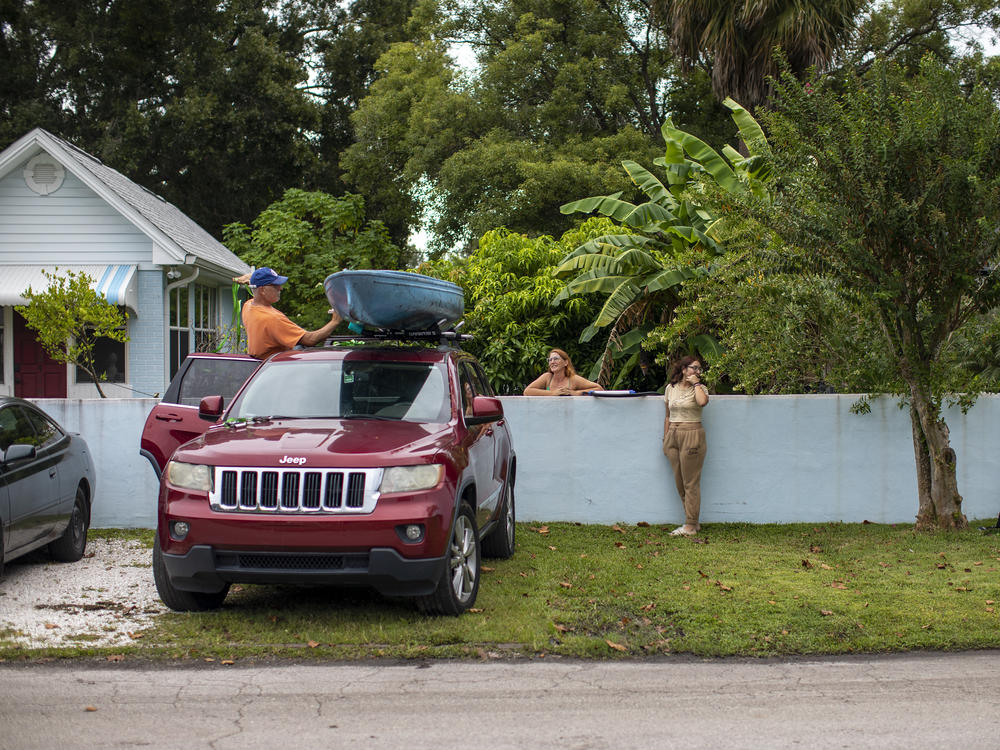 Allan Juhl ties up his canoe while his partner Katie Falcon and their neighbors Ashley Palacios and her brother Andres Garcia look on in the Palmetto Beach neighborhood of Tampa, Fla., on Tuesday. All of them are staying put for now.