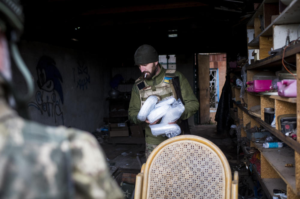 A soldier scavenges plastic cups and plates from a burnt-out home in Borshchova on Friday.