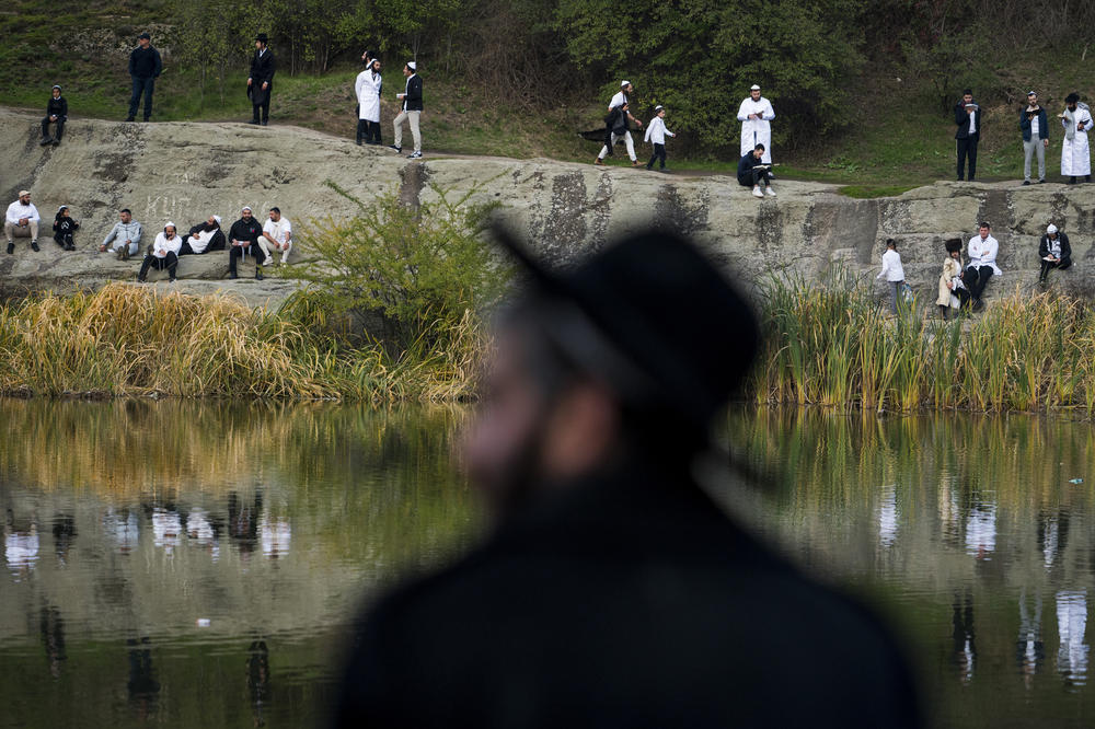 Hasidic pilgrims gather at a lake to perform Tashlikh, an atonement ritual that involves praying and symbolically casting one's sins into a body of water, during the Rosh Hashanah pilgrimage to Rabbi Nachman's tomb.