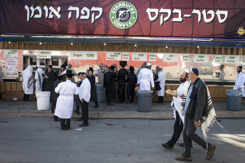 Pilgrims pass by a large banner with a parody Starbucks Coffee logo in Uman on Tuesday.