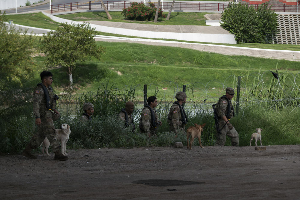 National Guard troops walk by the river banks of the Rio Grande.