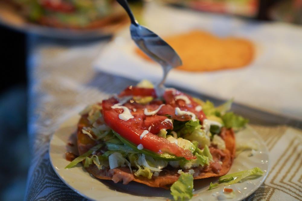 Carla Claure cooks simple meals for her family, like a tostada with refried beans, lettuce, avocado and tomato on a tortilla. She gets groceries from donations, food stamps and a food pantry.