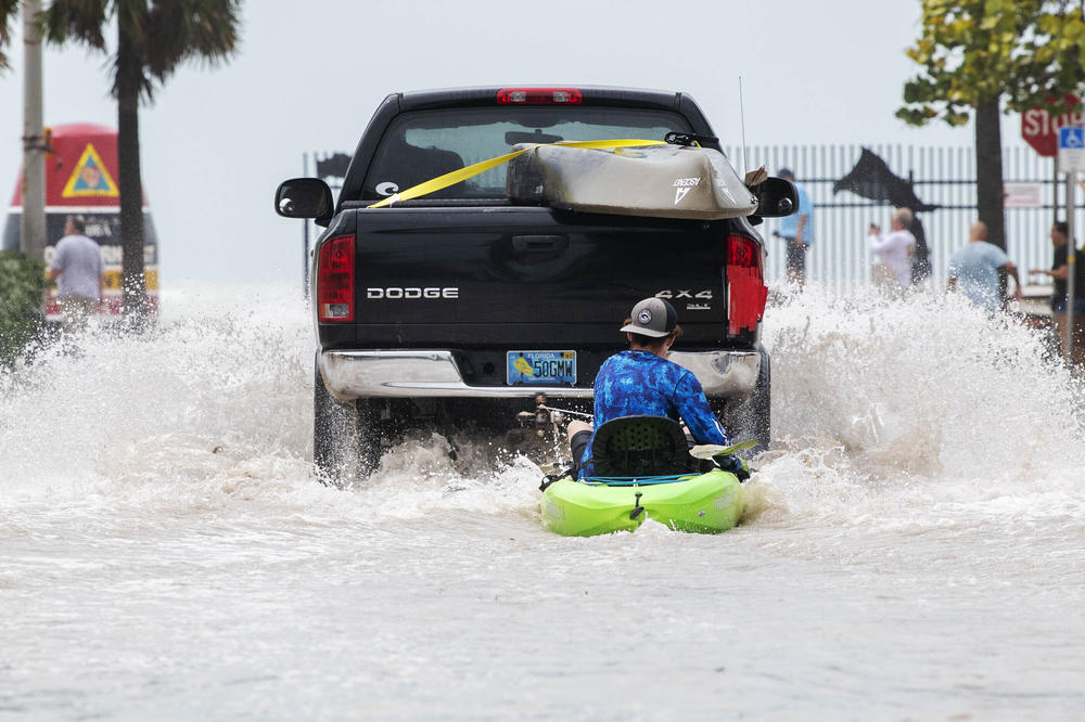 A truck pulls a man on a kayak on a low-lying road after flooding in the aftermath of Hurricane Ian, in Key West, Fla., Wednesday afternoon, Sept. 28, 2022.
