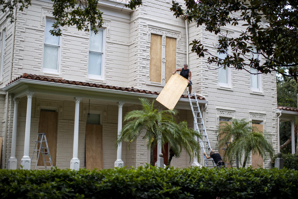 Two people work on boarding up a house in South Tampa, Fla., on Sept. 27, 2022, before Hurricane Ian hit the area.