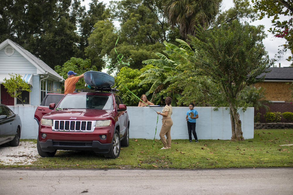Allan Juhl gets help tying up his canoe while his partner Katie Falcon and their neighbors Ashley Palacios and her brother Andres Garcia look on Sept. 27, 2022, in the Palmetto Beach neighborhood of Tampa, Fla., before Hurricane Ian hit the area.