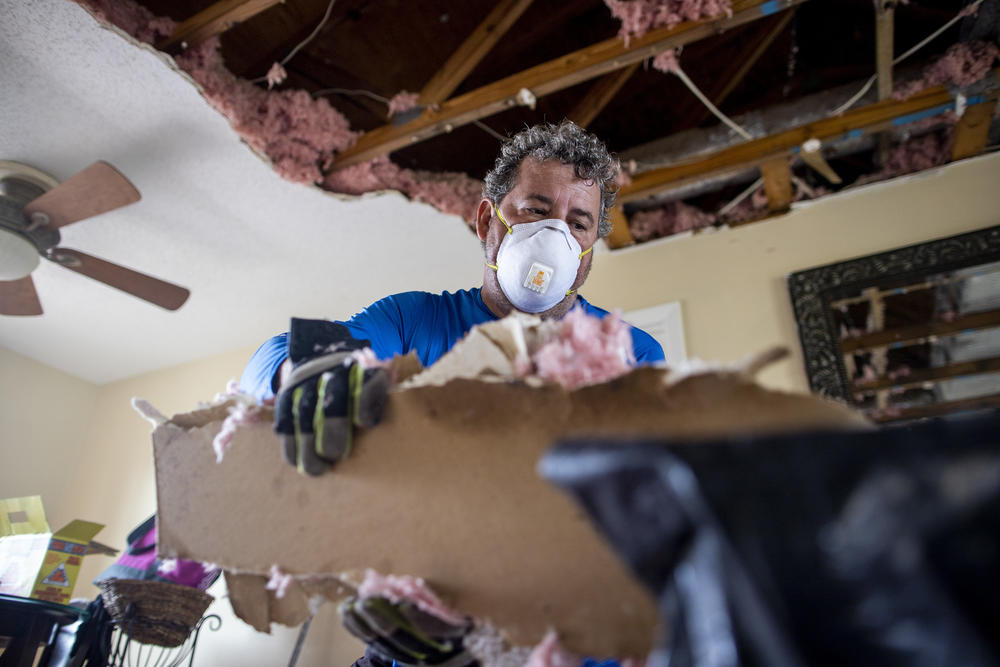 Larry Goerlatz cleans up pieces of his roof in Englewood Florida on September 29, 2022.
