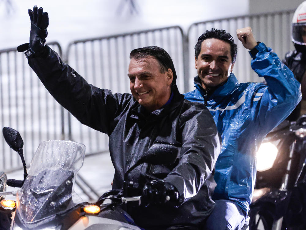 President Bolsonaro rides a motorbike with a supporter during a campaign rally in Santos on Wednesday.