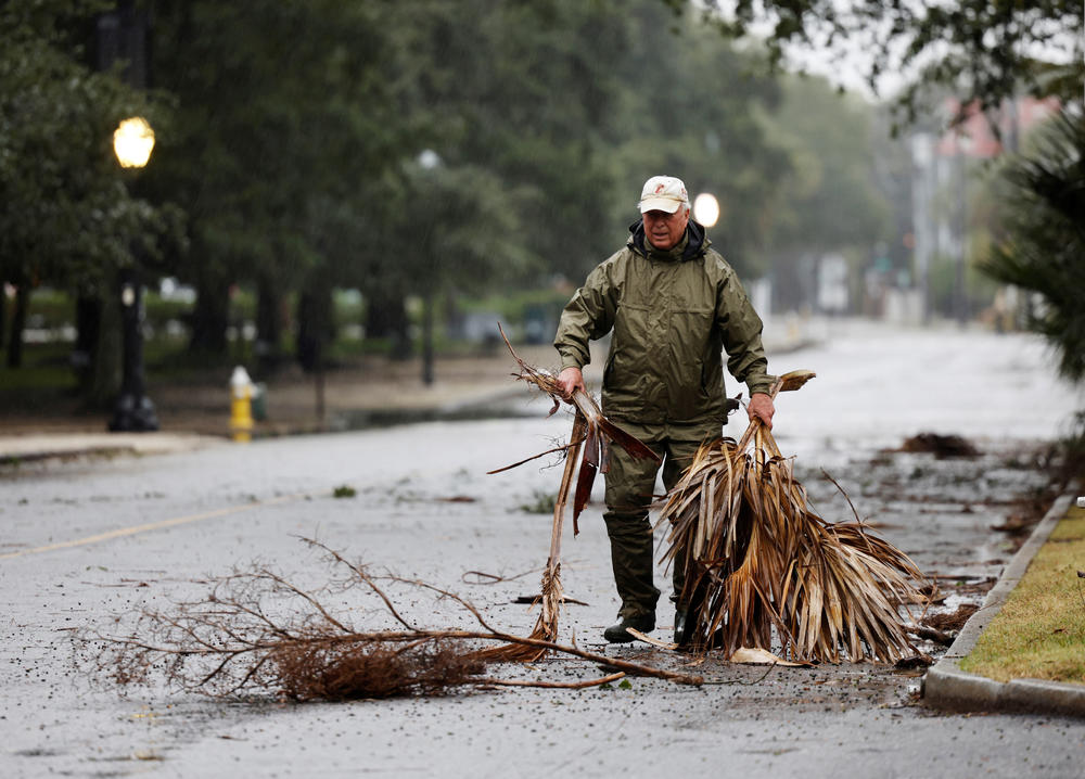 A local resident hauls debris from the road in an effort to keep gutter drains clear as hurricane Ian bears down on Charleston on Sept. 30.