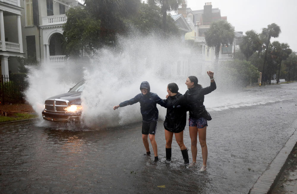 Young residents react as a truck sprays water while driving past them on a street flooded due to Hurricane Ian in Charleston on Sept. 30.