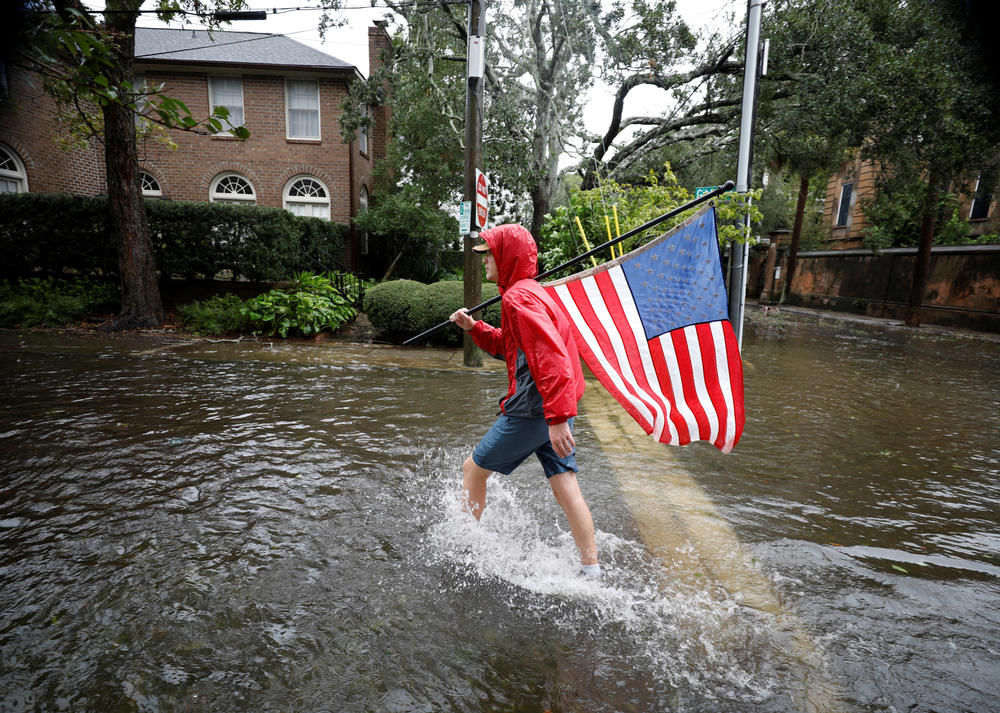 Caden Simmons, a 16-year-old local resident, walks with a U.S. flag on a flooded street after he recovered it from floodwaters in Charleston on Sept. 30.