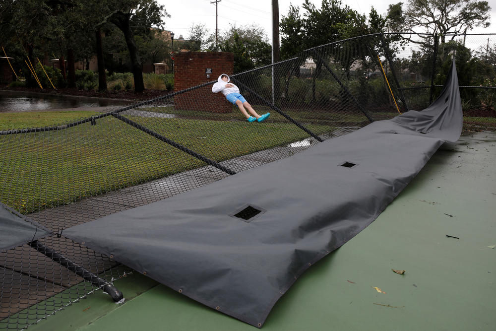 A local child lies on a collapsed tennis court fence as Hurricane Ian bears down on Charleston on Sept. 30.