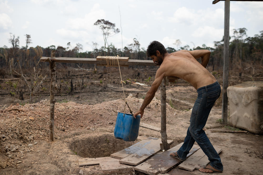 Marcelo Garcia, 45, gets water from a well at his home in an area of the Amazon that was deforested and burned in Amazonas, Brazil on Tuesday. The well is the only source of water at his home.