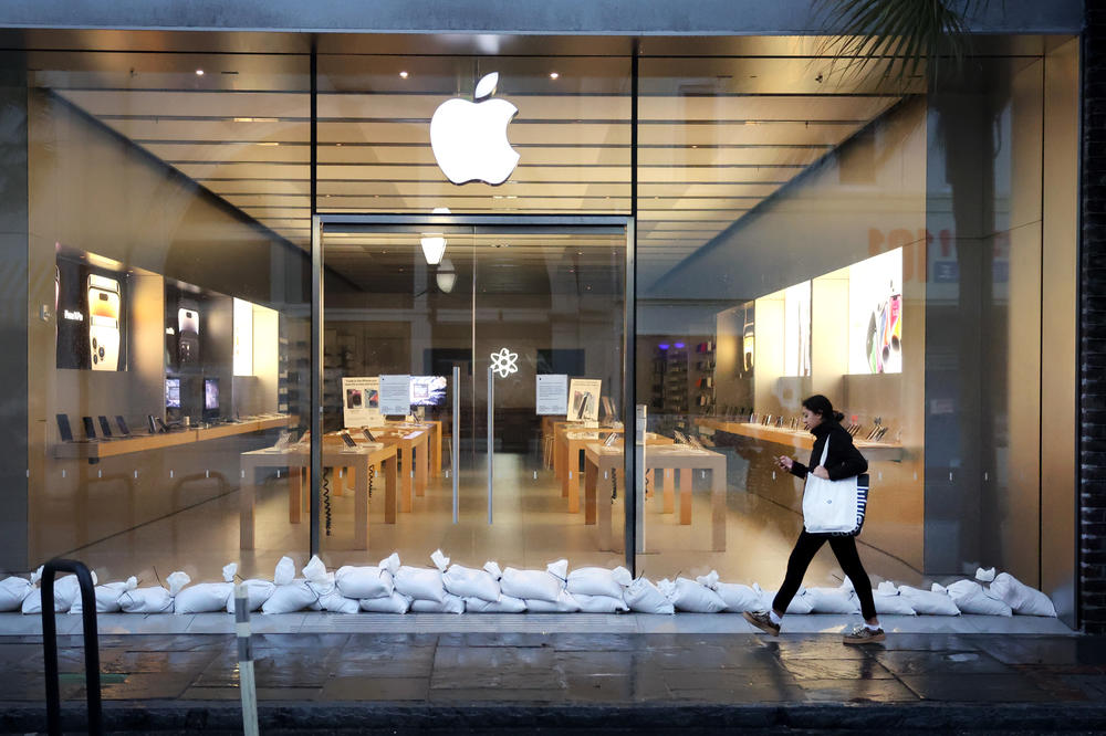 A woman walks past a shuttered Apple store in the historic district of Charleston as the city prepares for Hurricane Ian to make landfall on Sept. 30.