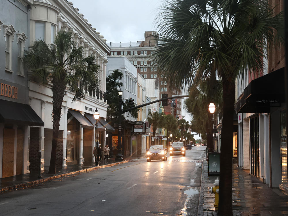 Cars drive through a nearly-deserted historic district in Charleston, S.C., as the city prepares for Hurricane Ian to make landfall Friday.