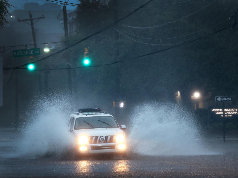 A vehicle is driven down a flooded street in Charleston, S.C., as rain from Hurricane Ian drenches the city on Friday.