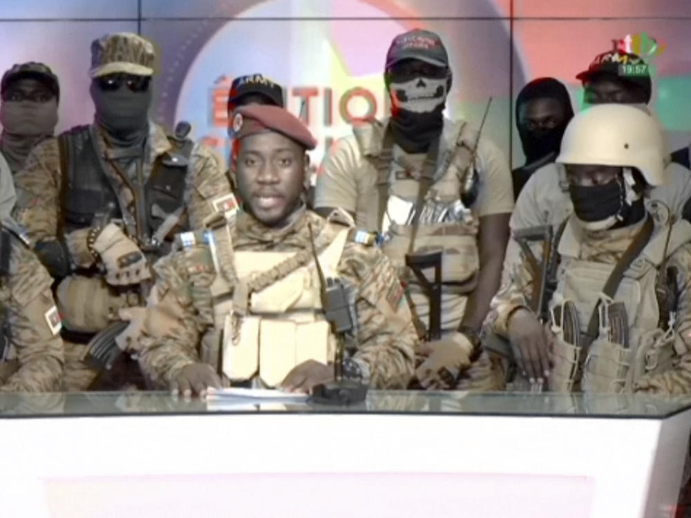 In this image from video broadcast by RTB state television, coup spokesman Capt. Kiswendsida Farouk Azaria Sorgho reads a statement in a studio in Ougadougou, Burkina Faso, on Friday evening.