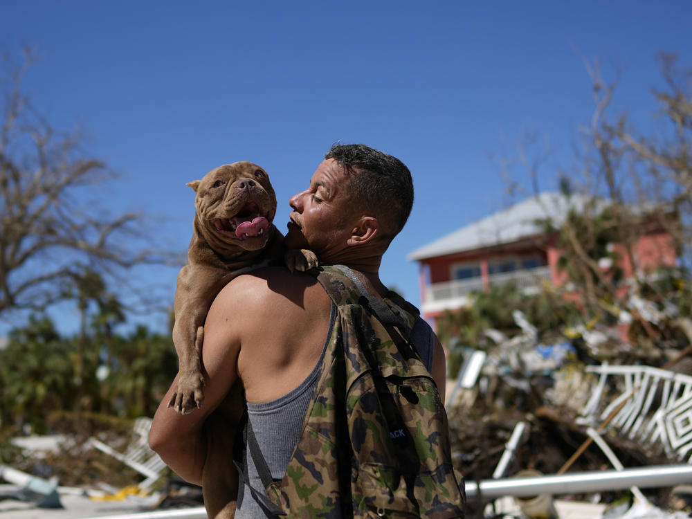 Eduardo Tocuya carries a dog he recovered in hopes of reuniting it with its owners, two days after the passage of Hurricane Ian, in Fort Myers Beach, Fla., on Friday.