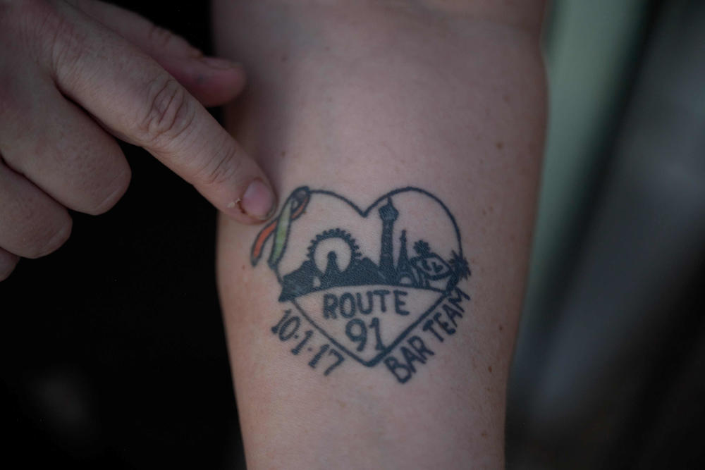 Heather Gooze shows a tattoo she got to commemorate Route 91. She's frustrated the city has yet to build a memorial on the site of the mass shooting. 