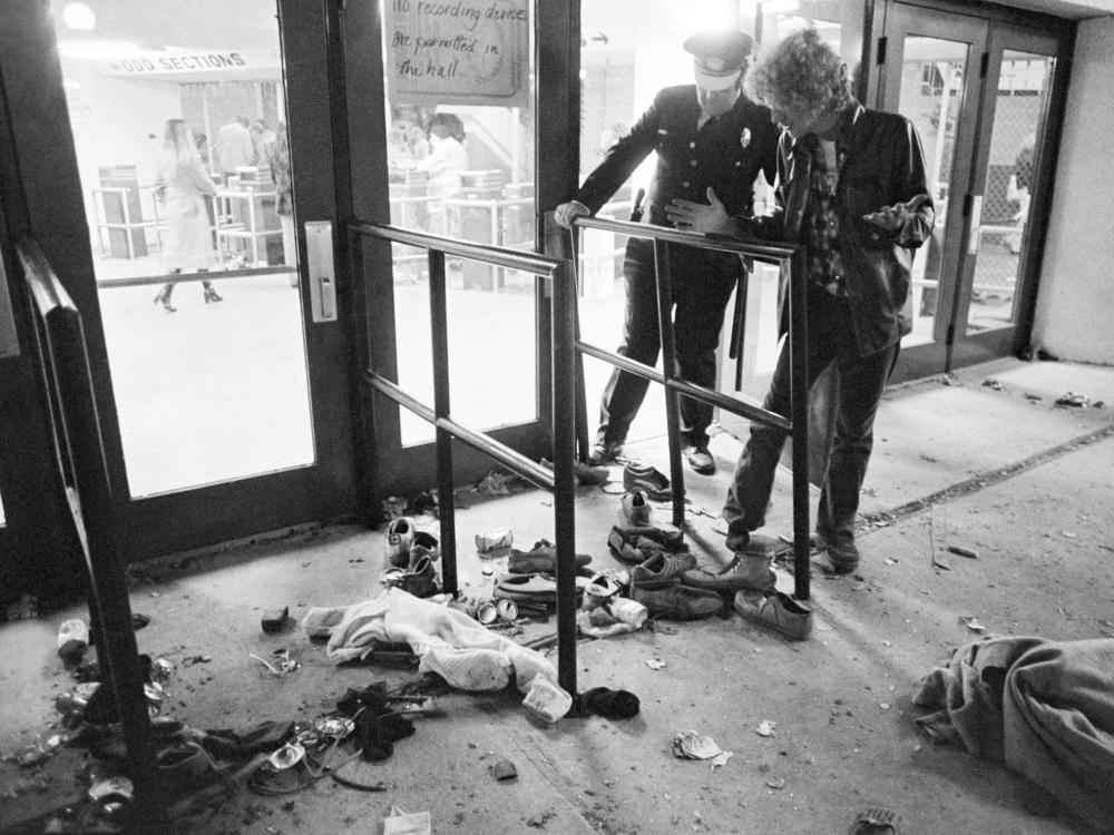 A security guard and an unidentified man look at an area where several people were killed as they were caught in a surging crowd entering Cincinnati's Riverfront Coliseum for a concert by The Who on Dec. 3, 1979.