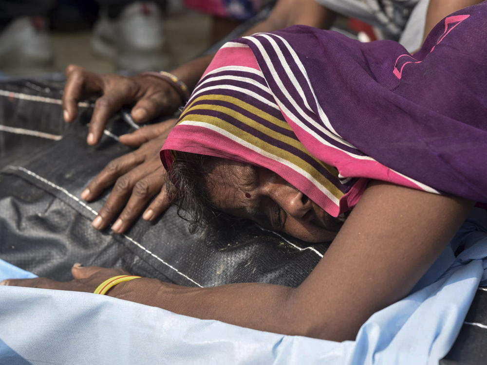A relative mourns near the body of one of victims of a road accident in Kanpur, Uttar Pradesh state, India, Sunday, Oct.2, 2022. A farm tractor pulling a wagon loaded with people overturned and fell into a pond in Kanpur city's Ghatampur area Saturday night killing 26 people, most of them women and children.