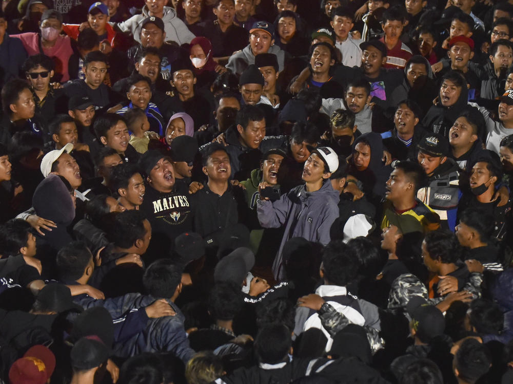 Soccer fans chant slogans during vigil for the victims of Saturday's soccer riots, in Malang, East Java, Indonesia, Sunday, Oct. 2, 2022.