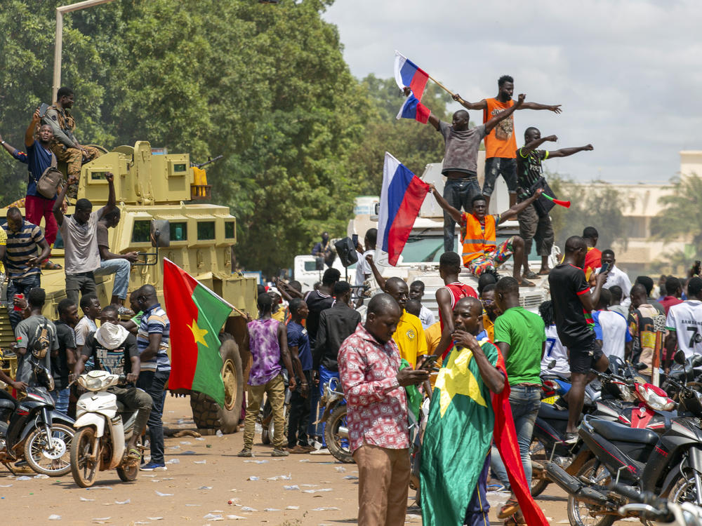 Supporters of Capt. Ibrahim Traore cheer with Russian flags in the streets of Ouagadougou, Burkina Faso, on Sunday. Burkina Faso's new junta leadership is calling for calm after the French Embassy and other buildings were attacked.