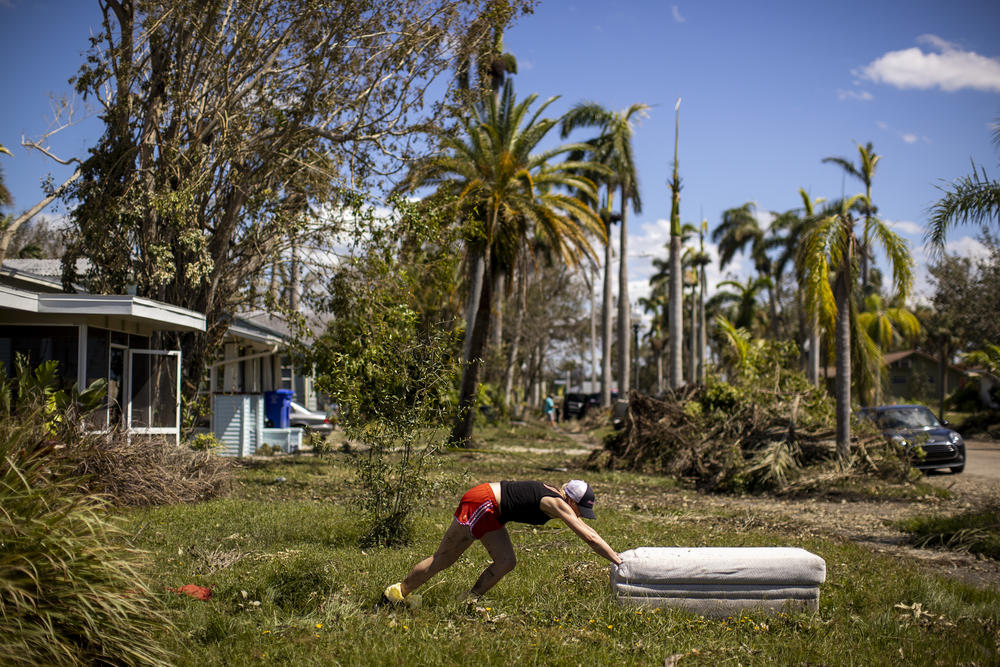 Lindsay Comstock removes ruined furniture from her home on Sunday in the Dean Park Historic District of Fort Myers, Fla. Comstock had evacuated with her family and had come back to her home to clean up.