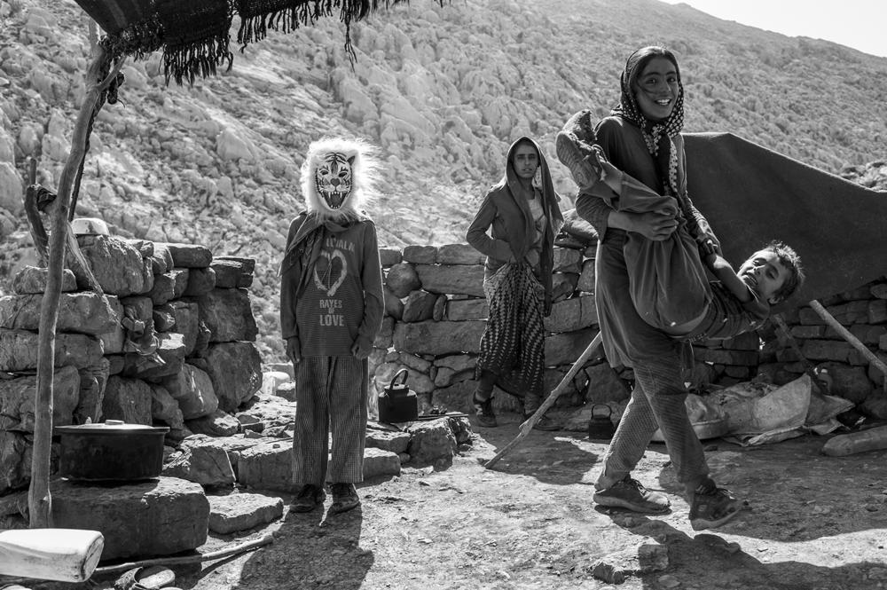 Bakhtiari youngsters enjoy a moment of fun. One of the kids is wearing a lion mask that his parents bought him on a trip they'd made to a city. Bakhtiari children typically study through middle school but do not attend high school.