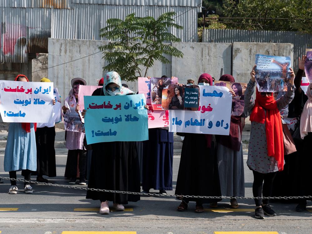 Afghan women hold placards as they take part in a protest in front of the Iranian embassy in Kabul on Thursday. Taliban forces fired shots into the air to disperse the rally.