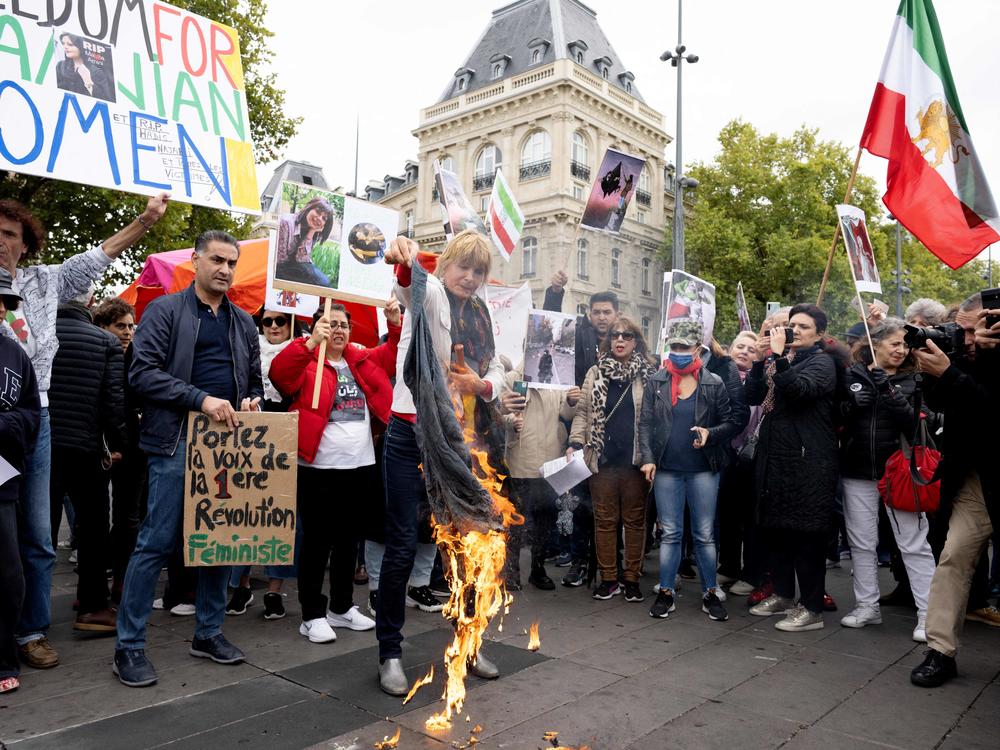 A woman burns headscarves during a demonstration in support of Kurdish Iranian woman Mahsa Amini during a protest on Sunday on Place de la Republique in Paris, following Amini's death in Iran.