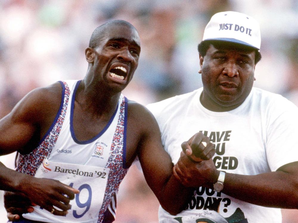 Great Britain's Derek Redmond limps to the finish line after tearing his hamstring at the 1992 Olympic Games, helped by his father Jim.