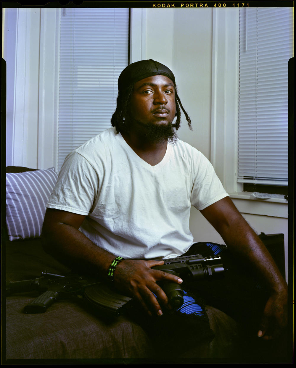 Chuck Chew, 36, sits on his bed with his firearm Wednesday, June 29, 2022, in Chicago. Chew provides professional bodyguard services to clients who prefer him dressed in plain clothes in order to blend into the community. 