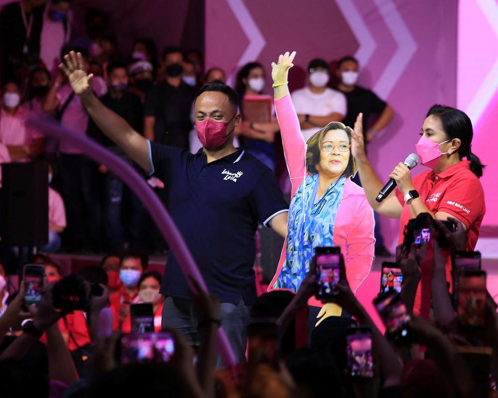 Then-Philippine Vice President and opposition presidential candidate Leni Robredo (right) endorses the senatorial candidacy of Leila de Lima next to a large cardboard cut out of de Lima, while de Lima's spokesperson Dino de Leon (left) looks on, during a campaign rally in Naga, Philippines. De Lima was running for reelection from jail.