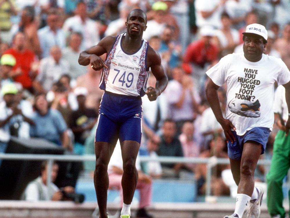 British runner Derek Redmond limps around the track toward the finish line at the 1992 Olympic Games after tearing his hamstring, as his father Jim races after him to offer help. Jim Redmond died this week at age 81.