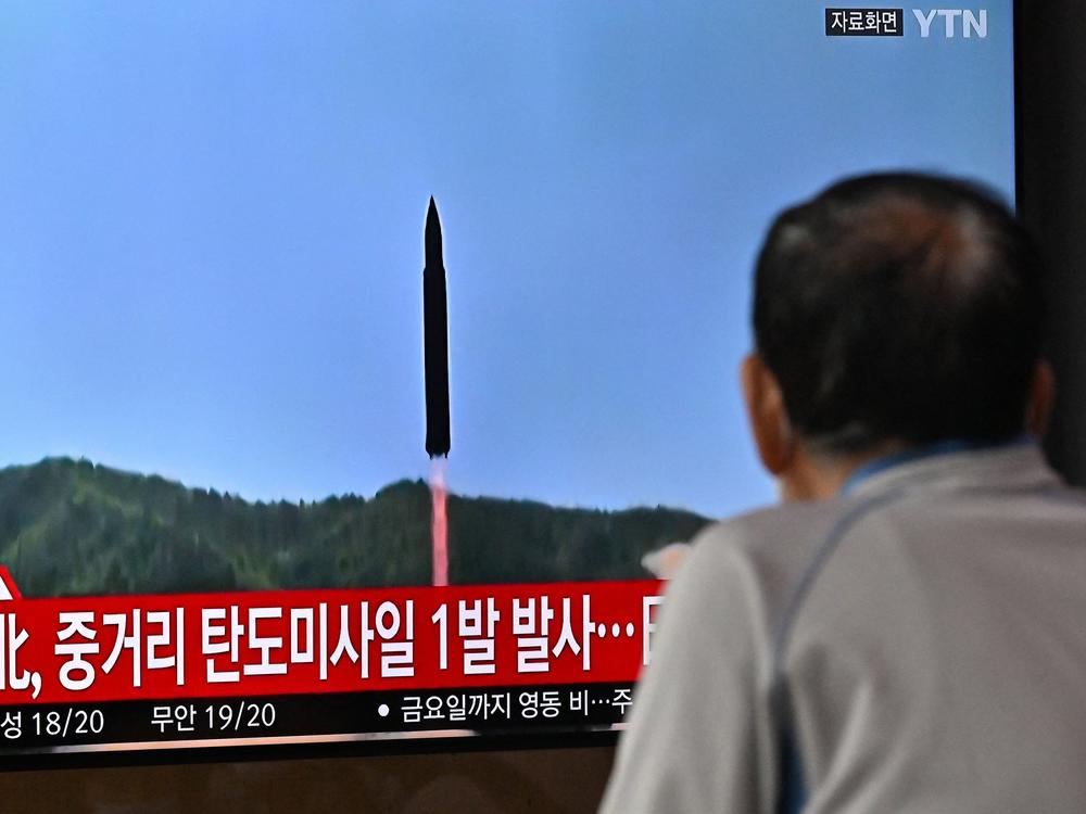 A man watches a television screen showing a news broadcast with file footage of a North Korean missile test, at a railway station in Seoul on October 4, 2022.