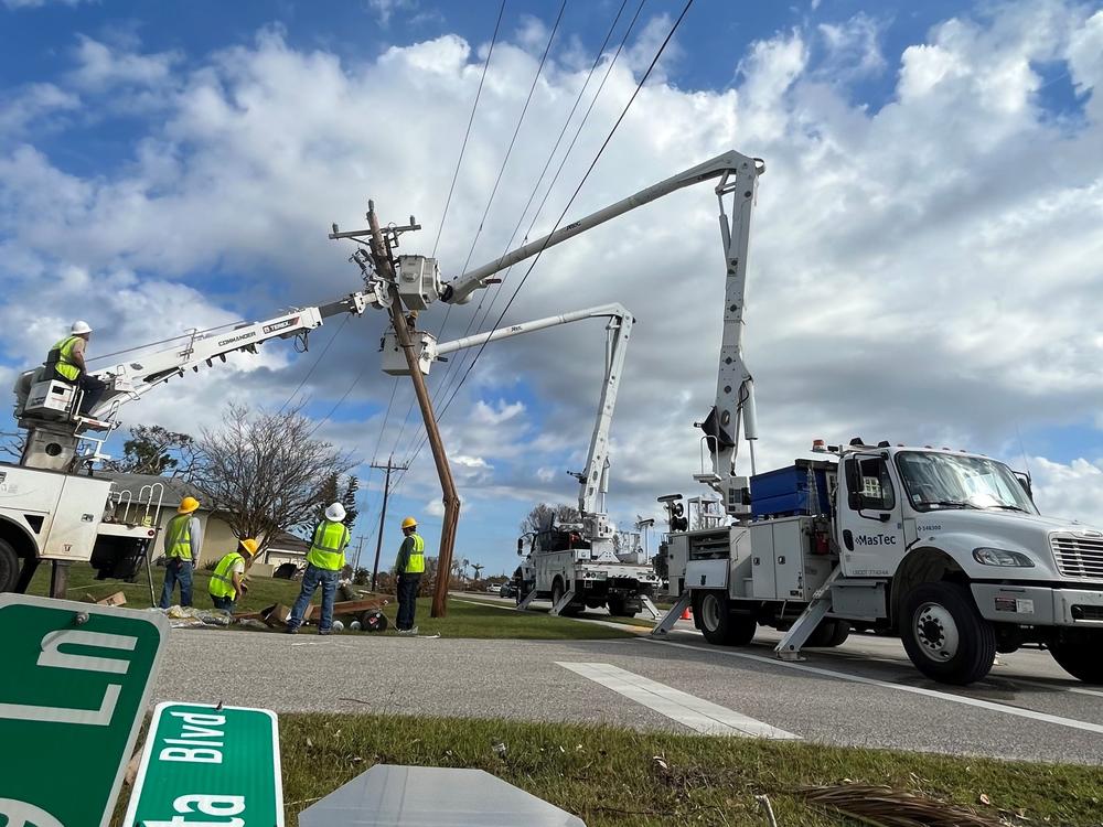 A power crew cuts a broken utility pole loose as they work to restore electricity in Cape Coral, Fla., after Hurricane Ian.
